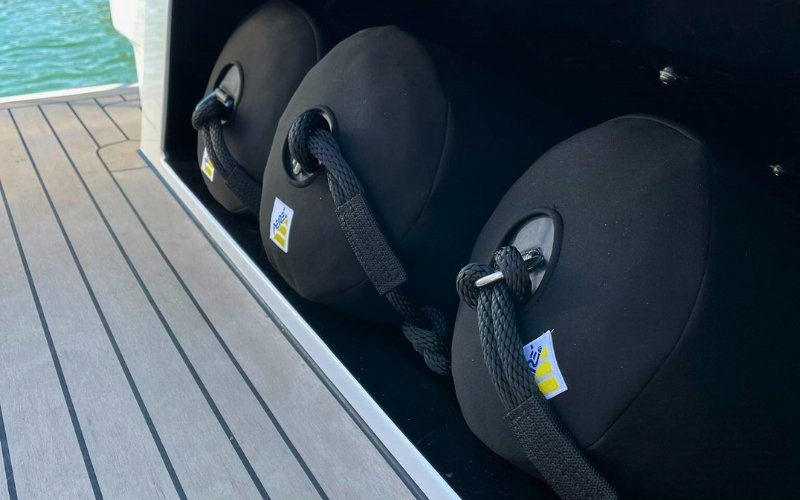 A wooden platform of a mega yacht with black fenders stored inside a dedicated storage compartment