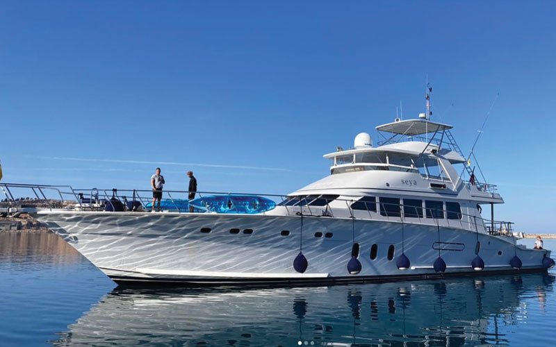 A luxurious mega yacht entering a marina, cruising through calm, azure waters.