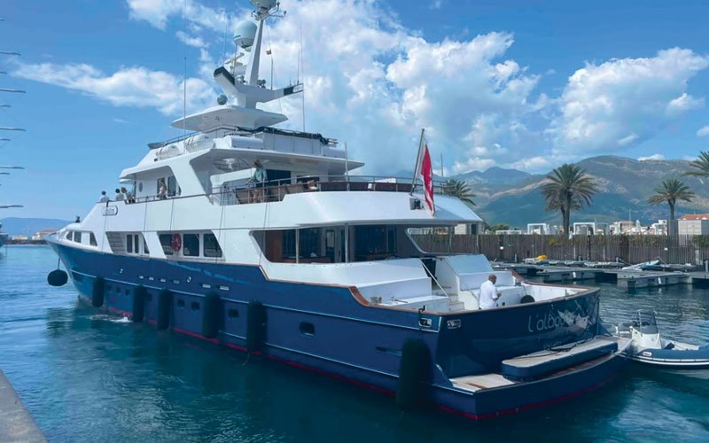 A luxurious mega yacht in blue and white colors, docked at a marina.