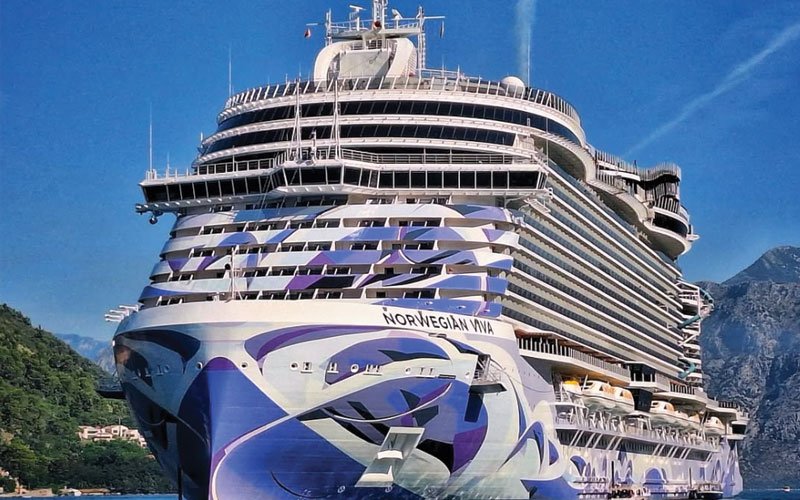 A large luxury cruise ship docked in a port, with a clear blue sky in the background