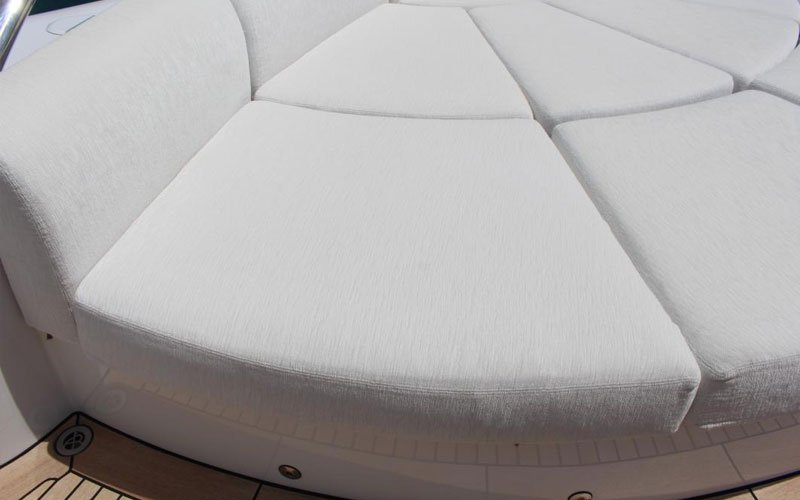 White, intricate, modern outdoor sofa on the deck of a yacht, designed by Argola Textile Yacht Design, offering a luxurious and comfortable seating area