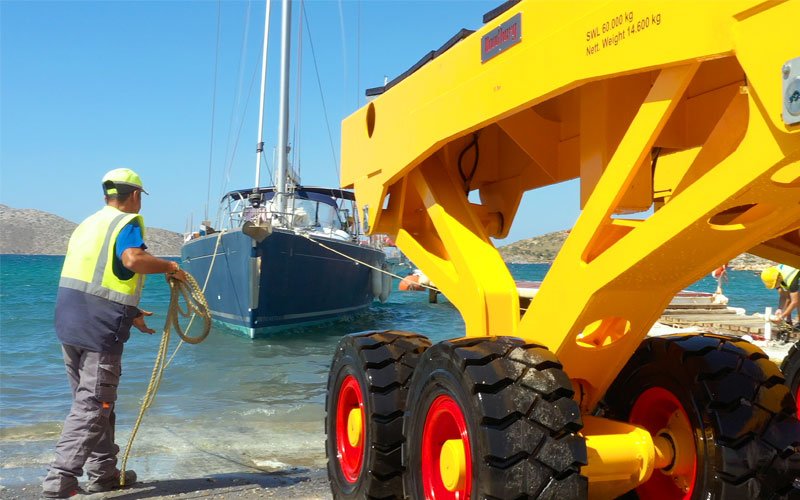 A yellow crane lifting a sailing yacht out of the water at Artemis Leros Boatyard, showcasing the boat hauling process
