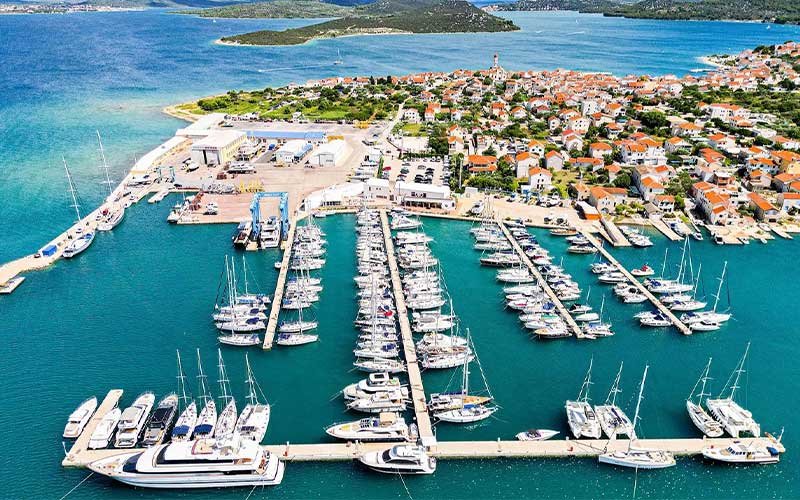 Marina Betina with small and large boats moored along its docks, surrounded by calm waters
