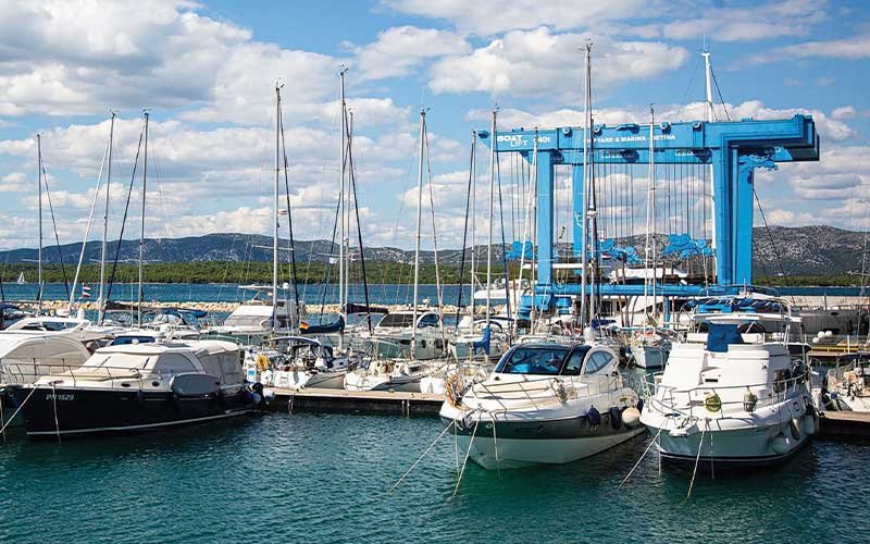 Marina Betina with small and large boats moored along its docks, featuring a shipyard within the marina by the calm waters