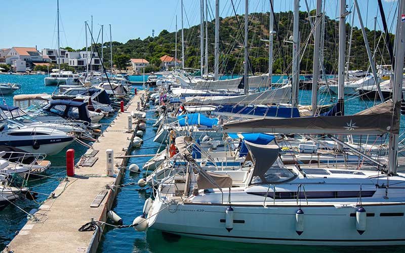 A row of sailing boats moored at the dock, neatly lined up against the calm waters