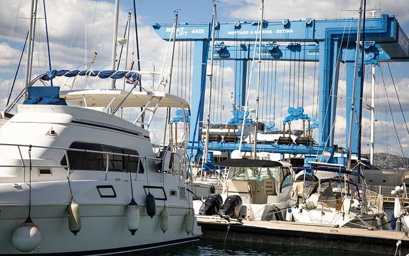 Marina Betina with small and large boats moored along its docks, featuring a shipyard within the marina by the calm waters