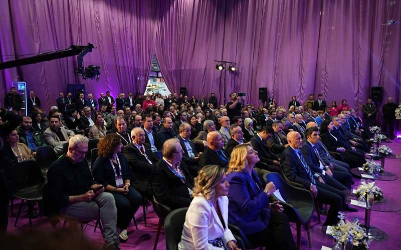 Attendees, including people in formal, are seated in a purple-draped hall at the Bosphorus Boat Show event.