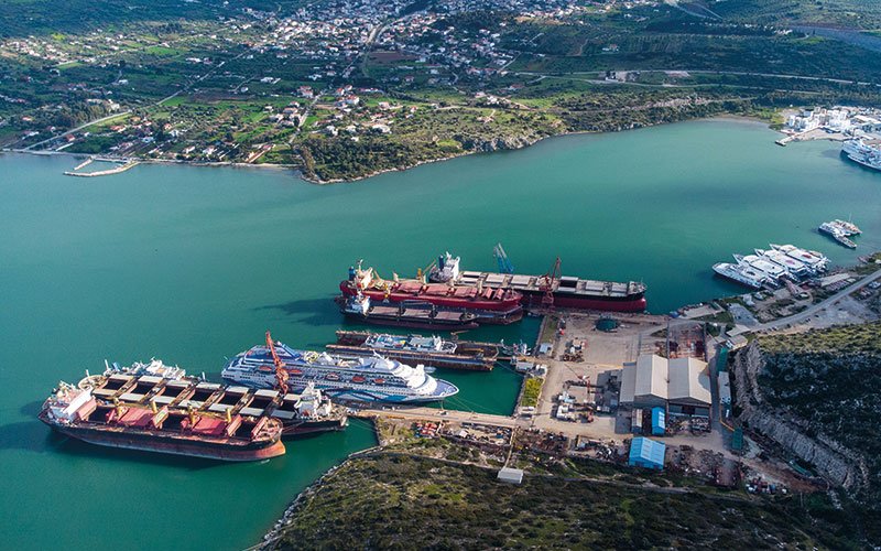 Aerial view of Chalkis Shipyards in Greece showing the ship repair and maintenance facilities, docks, and commercial vessels moored in the bay surrounded by coastal landscape.