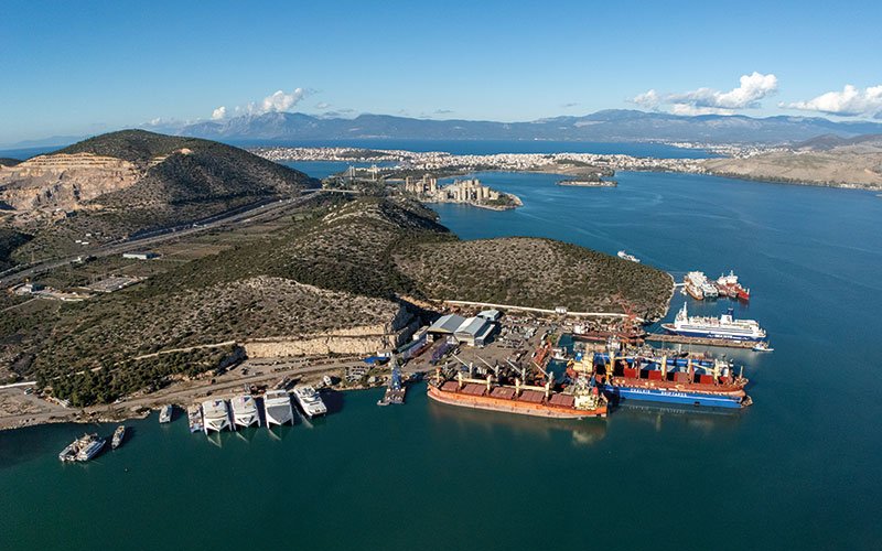 Aerial view of Chalkis Shipyards in Greece showing the ship repair and maintenance facilities, docks, and commercial vessels moored in the bay surrounded by coastal landscape.