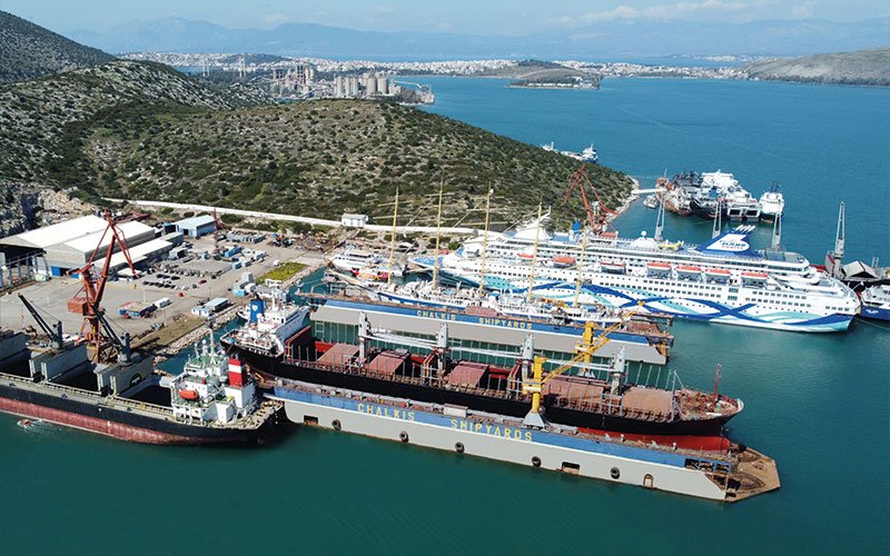 Close aerial view of Chalkis Shipyards with cruise ships, superyachts, and commercial vessels in dry dock and alongside the quay for repair, refit, and maintenance services.