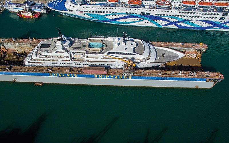 Close aerial view of Chalkis Shipyards with cruise ships, superyachts, and commercial vessels in dry dock and alongside the quay for repair, refit, and maintenance services.
