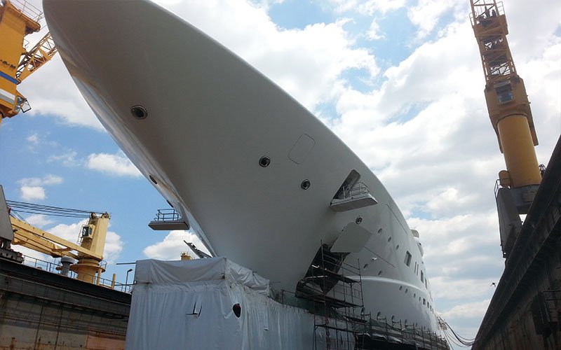 Close aerial view of Chalkis Shipyards with cruise ships, superyachts, and commercial vessels in dry dock and alongside the quay for repair, refit, and maintenance services.