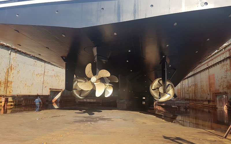 Close aerial view of Chalkis Shipyards with cruise ships, superyachts, and commercial vessels in dry dock and alongside the quay for repair, refit, and maintenance services.
