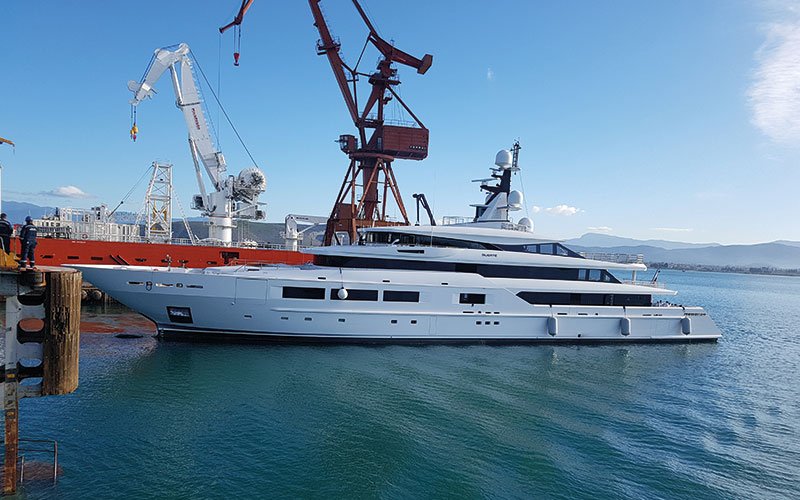 Close aerial view of Chalkis Shipyards with cruise ships, superyachts, and commercial vessels in dry dock and alongside the quay for repair, refit, and maintenance services.