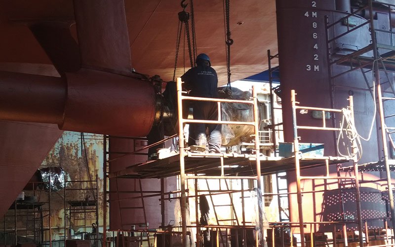 Skilled technicians working at Chalkis Shipyards performing welding, structural steel repairs, and propeller maintenance on vessels during ship repair and refit operations.