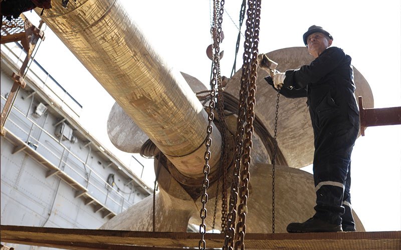Skilled technicians working at Chalkis Shipyards performing welding, structural steel repairs, and propeller maintenance on vessels during ship repair and refit operations.