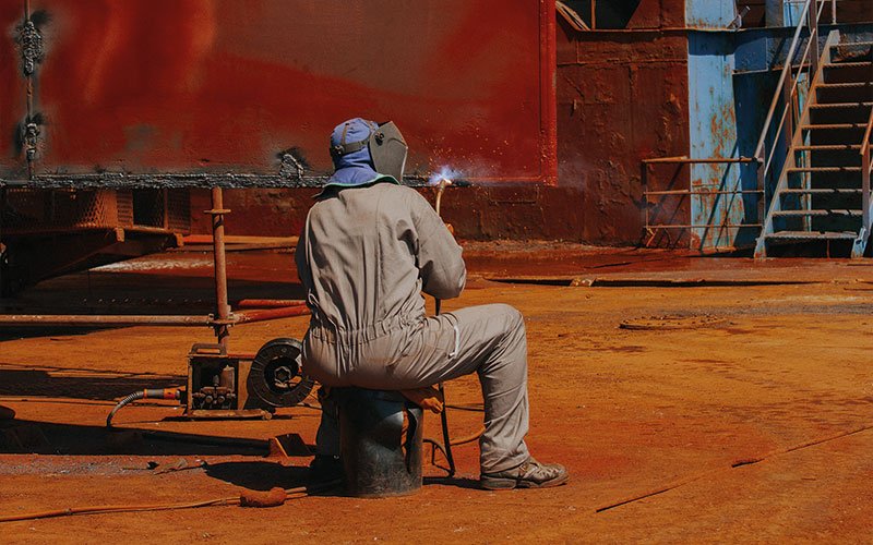Skilled technicians working at Chalkis Shipyards performing welding, structural steel repairs, and propeller maintenance on vessels during ship repair and refit operations.