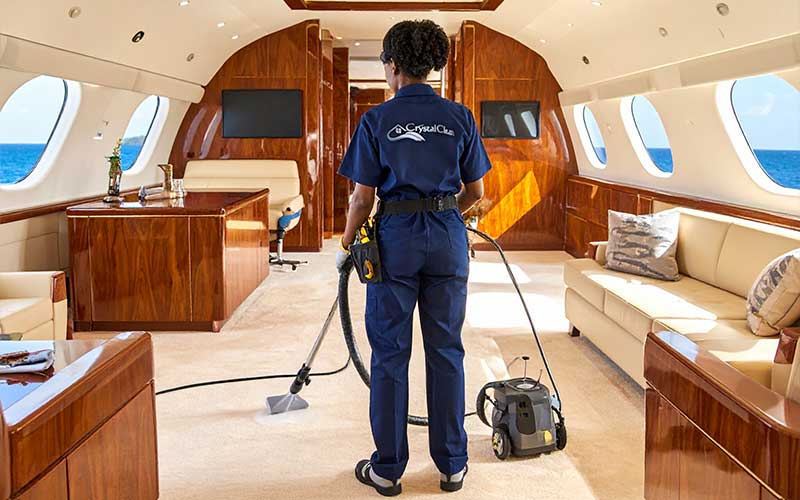 Crystal Clean technician vacuuming yacht carpet with high‑power marine vacuum cleaner.