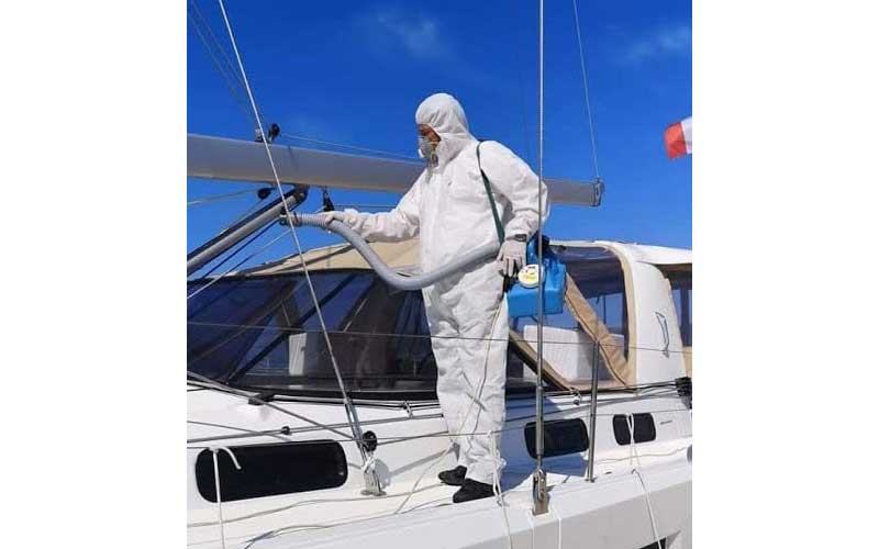 Crystal Clean exterior cleaning expert washing yacht deck in protective suit for full hygiene.