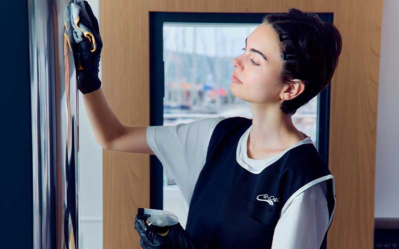 Crystal Clean crew member polishing yacht glass panel with professional cleaning tools.