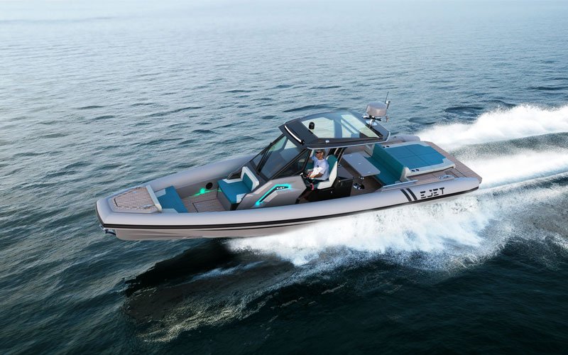 Ejet electric speedboat cruising at high speed on the open sea, featuring a modern design with a glass cockpit, blue and grey seating, and a person at the helm