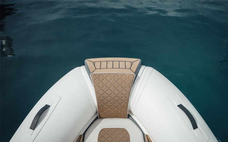Front view of a white Ejet electric tender boat with beige seating, positioned above greenish-blue sea water