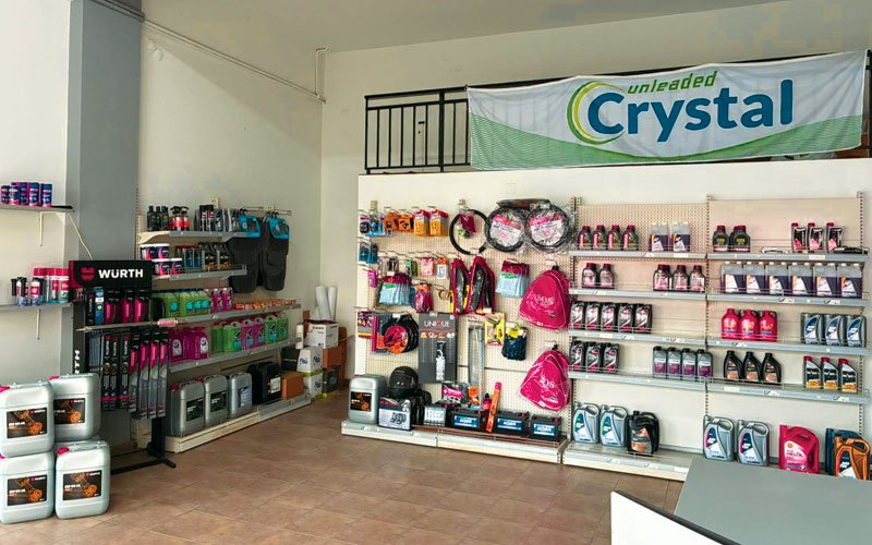 Interior of a gas station convenience area displaying various automotive products such as motor oils, car accessories, cleaning supplies, batteries, and branded merchandise.