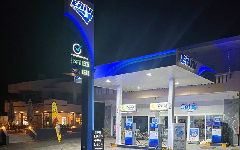 A fuel station branded with 'ΕΛΙΝ' (ELIN), a Greek petroleum company. The station includes a canopy over the pumps, a price sign showing fuel rates, and a white ELIN fuel truck parked nearby.