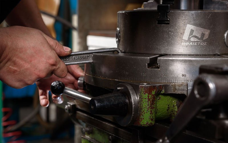 Precision adjustment of CNC milling machine by engineer at General Constructions Ifaistus manufacturing workshop