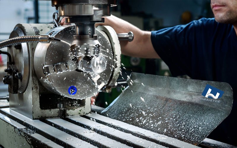 Heavy-duty CNC machining of metal block with coolant at General Constructions Ifaistus production facility.