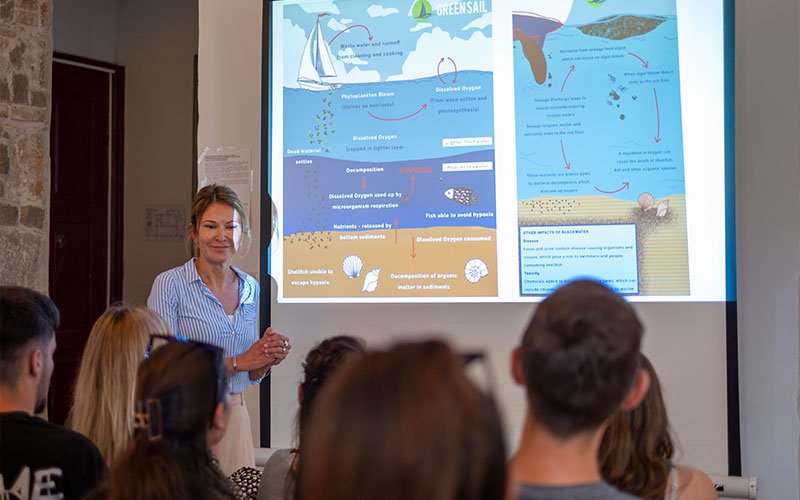 Α woman lectures and explains via video wall to the audience about the concept of Green Sail.
