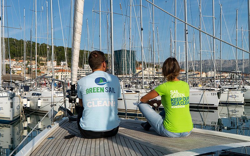 A man and a woman sitting on a sailing boat and looking at the sea and at the others yacht at the port