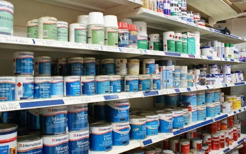 Interior of the LIANOS NIKOLAOS store showcasing a wide range of marine supplies, including ropes, paints, cleaning products, lubricants, flags, boat steering wheels, and various marine accessories neatly organized on shelves.