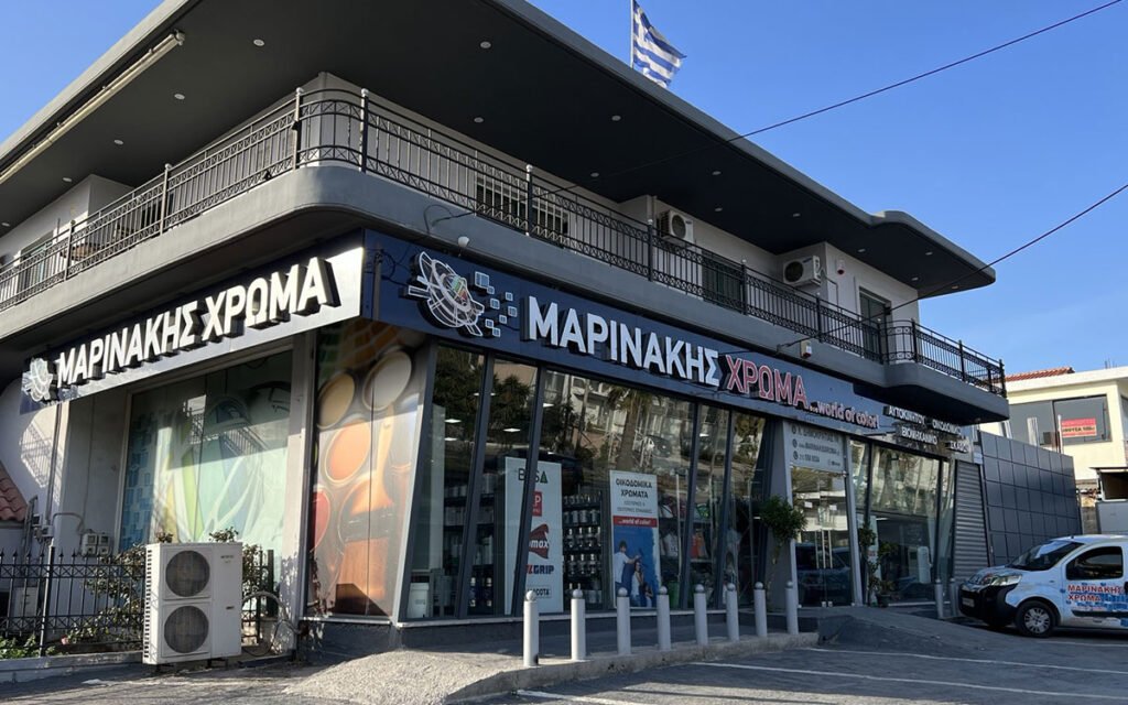 A storefront showing "Marinakis Xroma" with large windows displaying products, bold signage, and a welcoming, colorful exterior design.