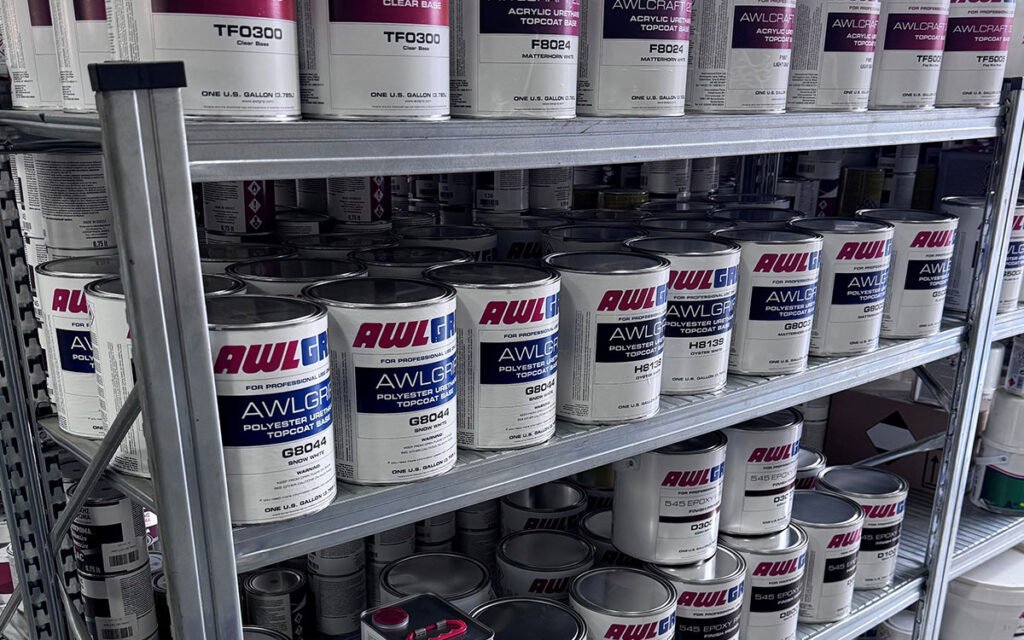An interior view of "Marinakis Xroma" showing neatly arranged shelves stocked with a variety of paint products and tools.