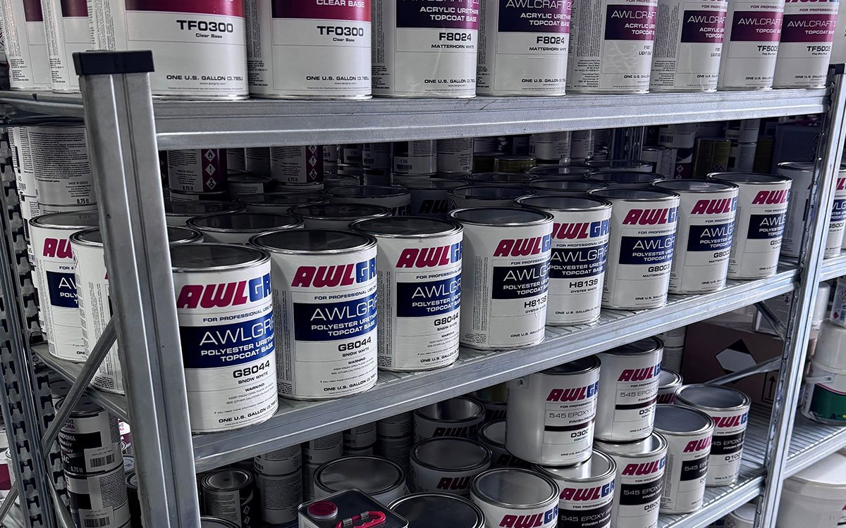 An interior view of "Marinakis Xroma" showing neatly arranged shelves stocked with a variety of paint products and tools.