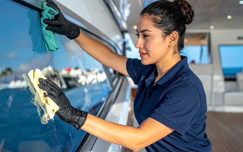 Detailer using microfiber cloths to clean and polish large yacht windows.