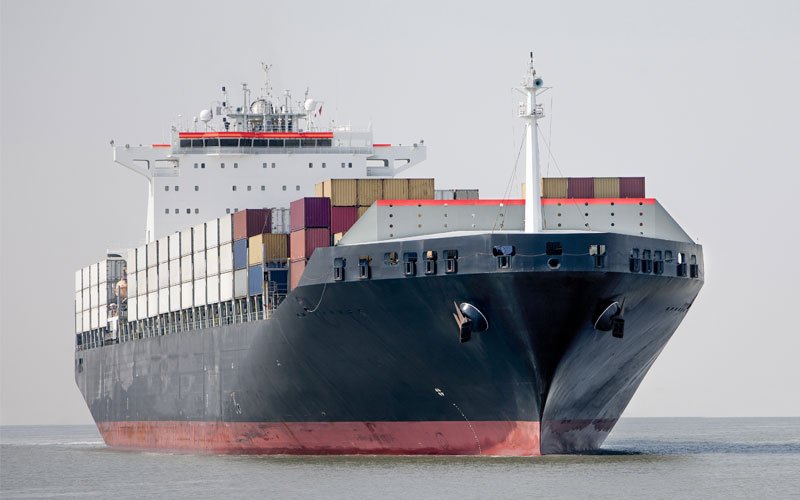 Cargo Ship carrying cargo in grey sea and sky.