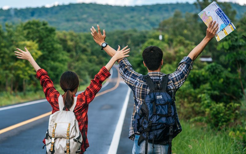 couple of tourists, in front of a country road, hands up, holding map