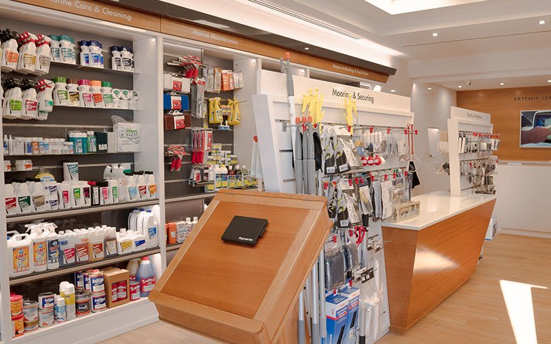 Interior view of Naval Store Yacht Supplies by Artemis Leros Boatyard, featuring light wood furniture and various products on display