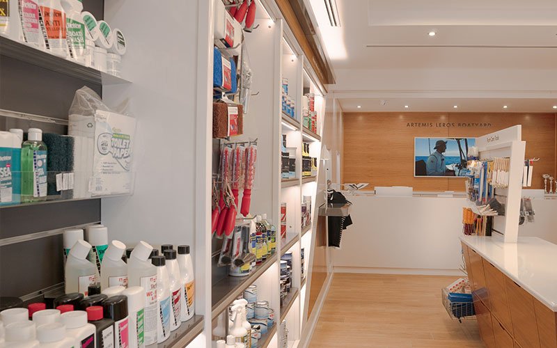 Interior view of Naval Store Yacht Supplies by Artemis Leros Boatyard, featuring light wood furniture and various products on display