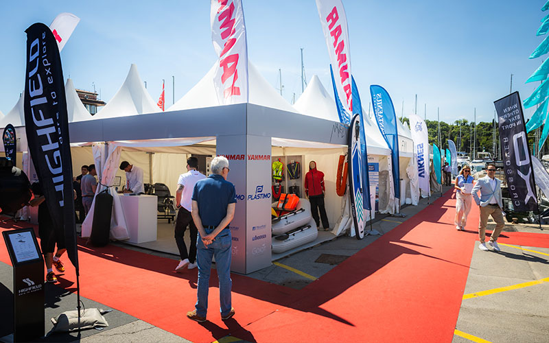 NAVELA exhibition stand at an international marine trade show with visitors and exhibitors.