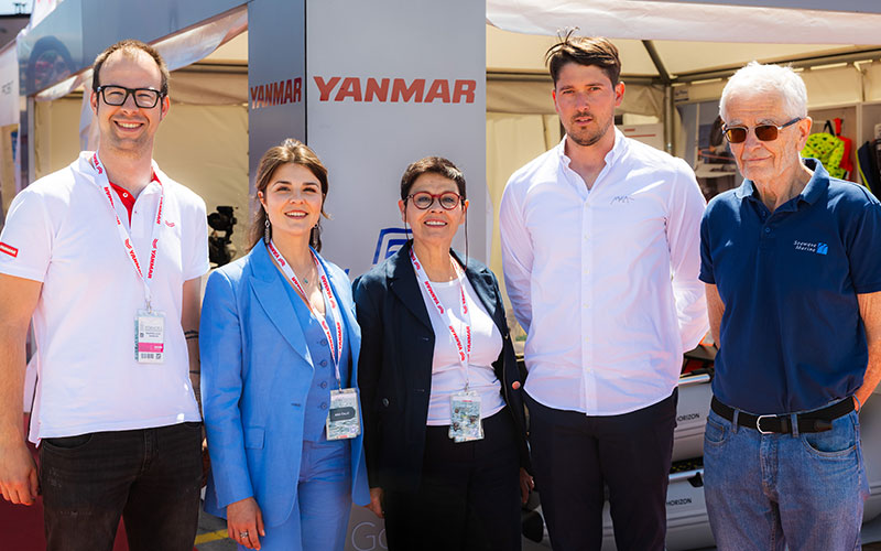 NAVELA team posing in front of the company exhibition booth at an international marine trade show.