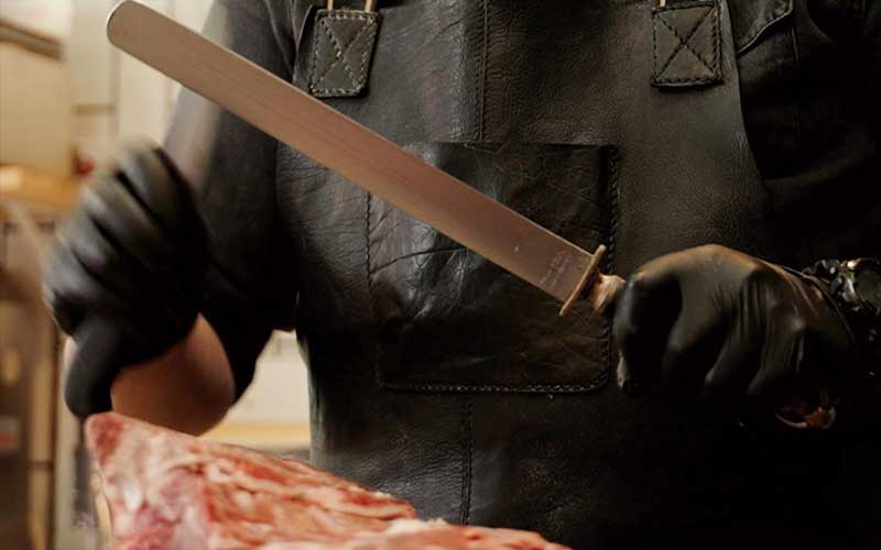 Professional butcher sharpening knife at SOUVATZOGLOU Yacht Meat Delivery before premium meat preparation