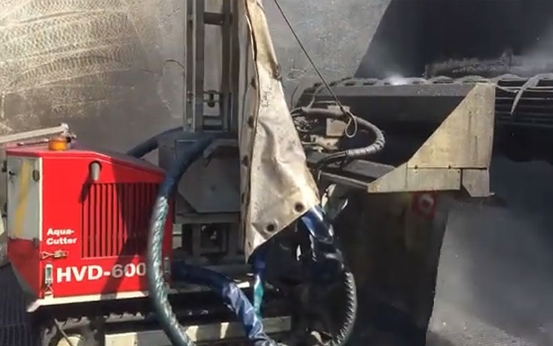 An industrial hydrodemolition robot labeled 'Aqua Cutter HVD-600' removes concrete or coating from a surface using high-pressure water jets