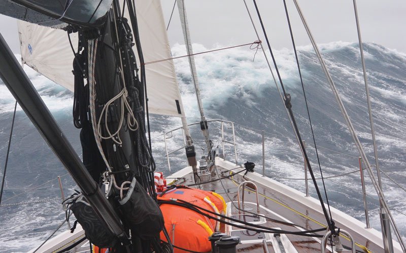 Sailing yacht equipped with Turtle-Pac flexible bladder tanks and liferaft gear, crew handling marine safety equipment during offshore sailing in rough seas and polar environments.