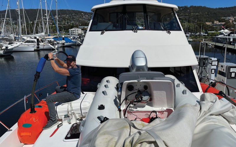 Sailing yacht equipped with Turtle-Pac flexible bladder tanks and liferaft gear, crew handling marine safety equipment during offshore sailing in rough seas and polar environments.