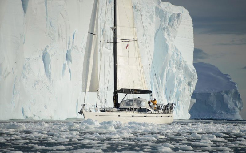 Sailing yacht equipped with Turtle-Pac flexible bladder tanks and liferaft gear, crew handling marine safety equipment during offshore sailing in rough seas and polar environments.