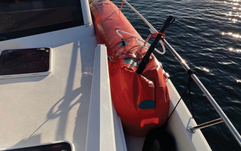 Sailing yacht equipped with Turtle-Pac flexible bladder tanks and liferaft gear, crew handling marine safety equipment during offshore sailing in rough seas and polar environments.
