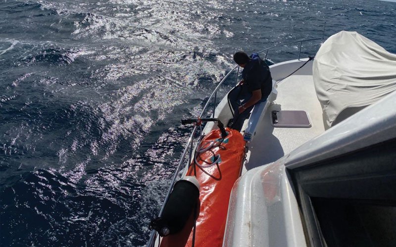 Sailing yacht equipped with Turtle-Pac flexible bladder tanks and liferaft gear, crew handling marine safety equipment during offshore sailing in rough seas and polar environments.
